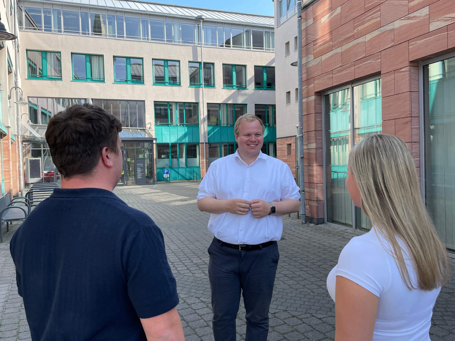 Кметът Макс Брайтенбах разговаря с двама души във вътрешния двор на кметството