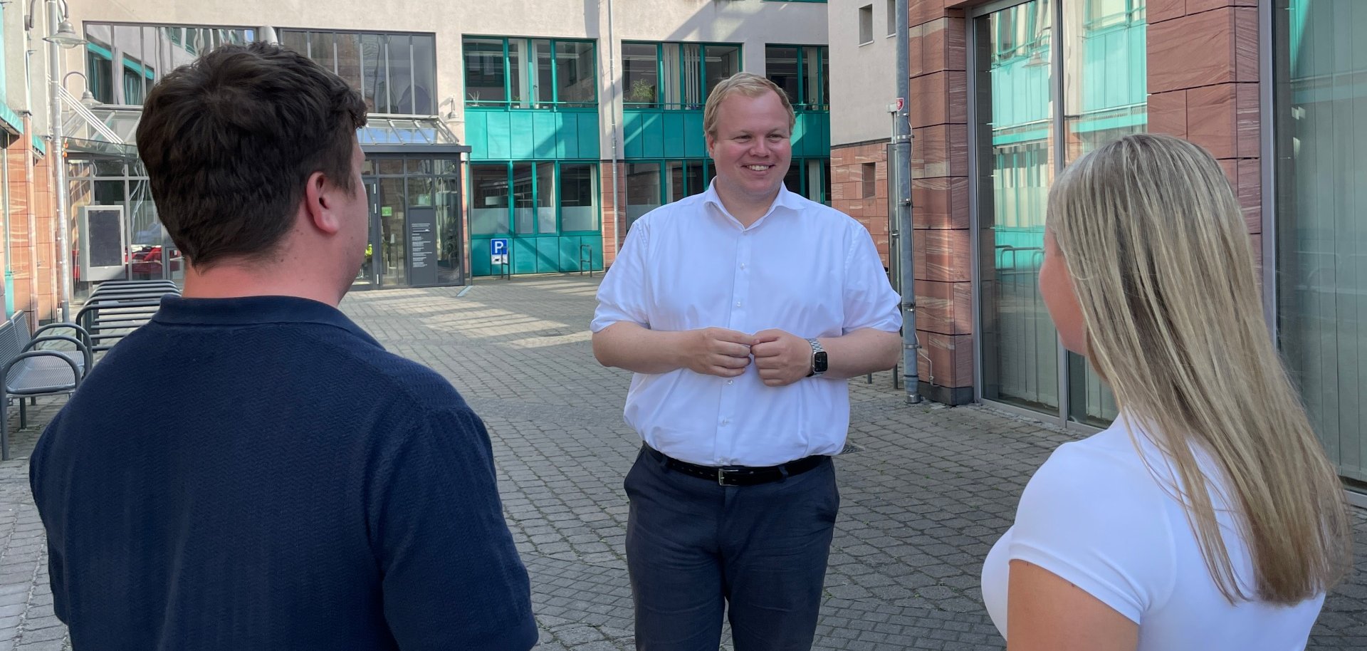 Mayor Max Breitenbach talks to two people in the inner courtyard of the town hall