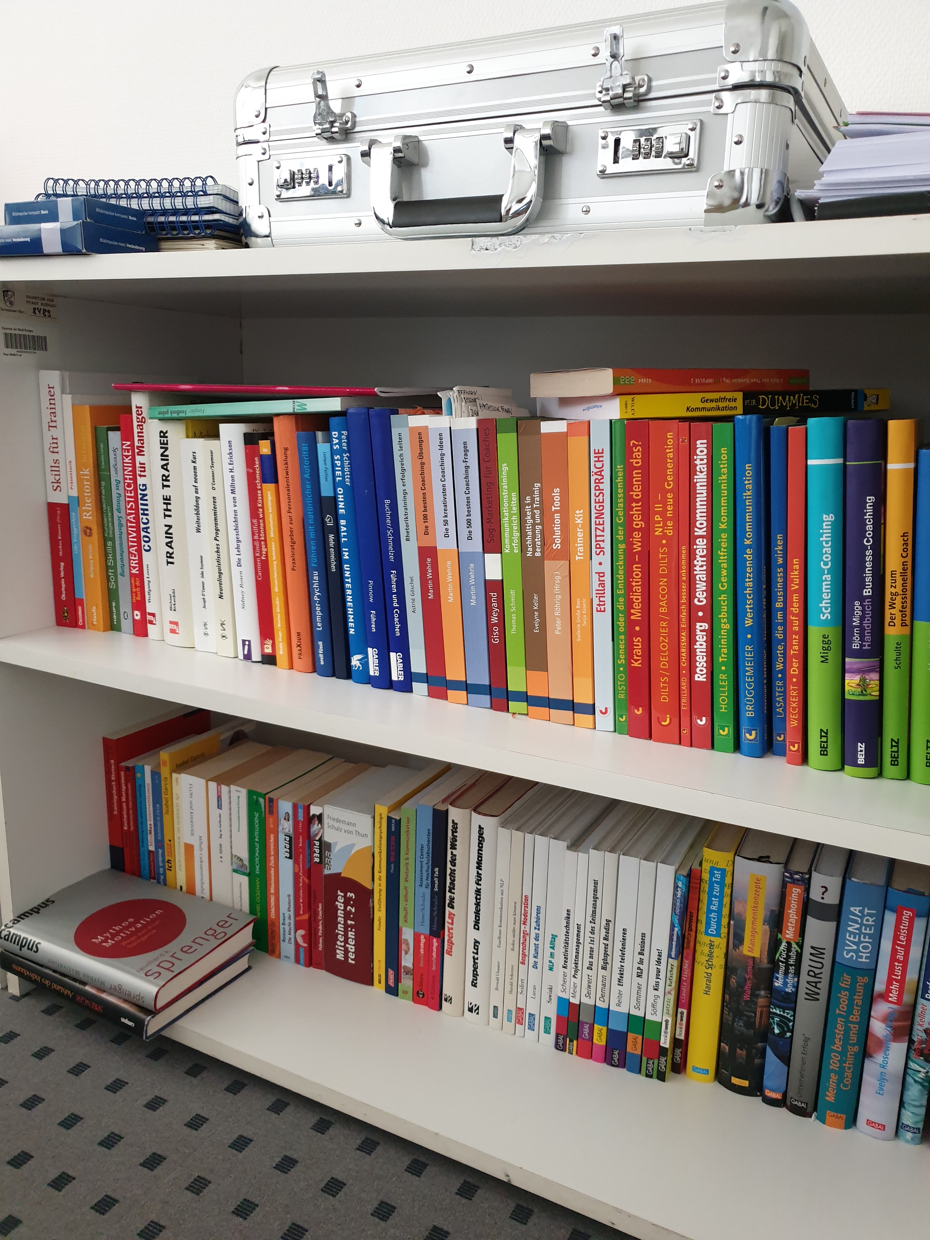 many different colourful books on a shelf in a library