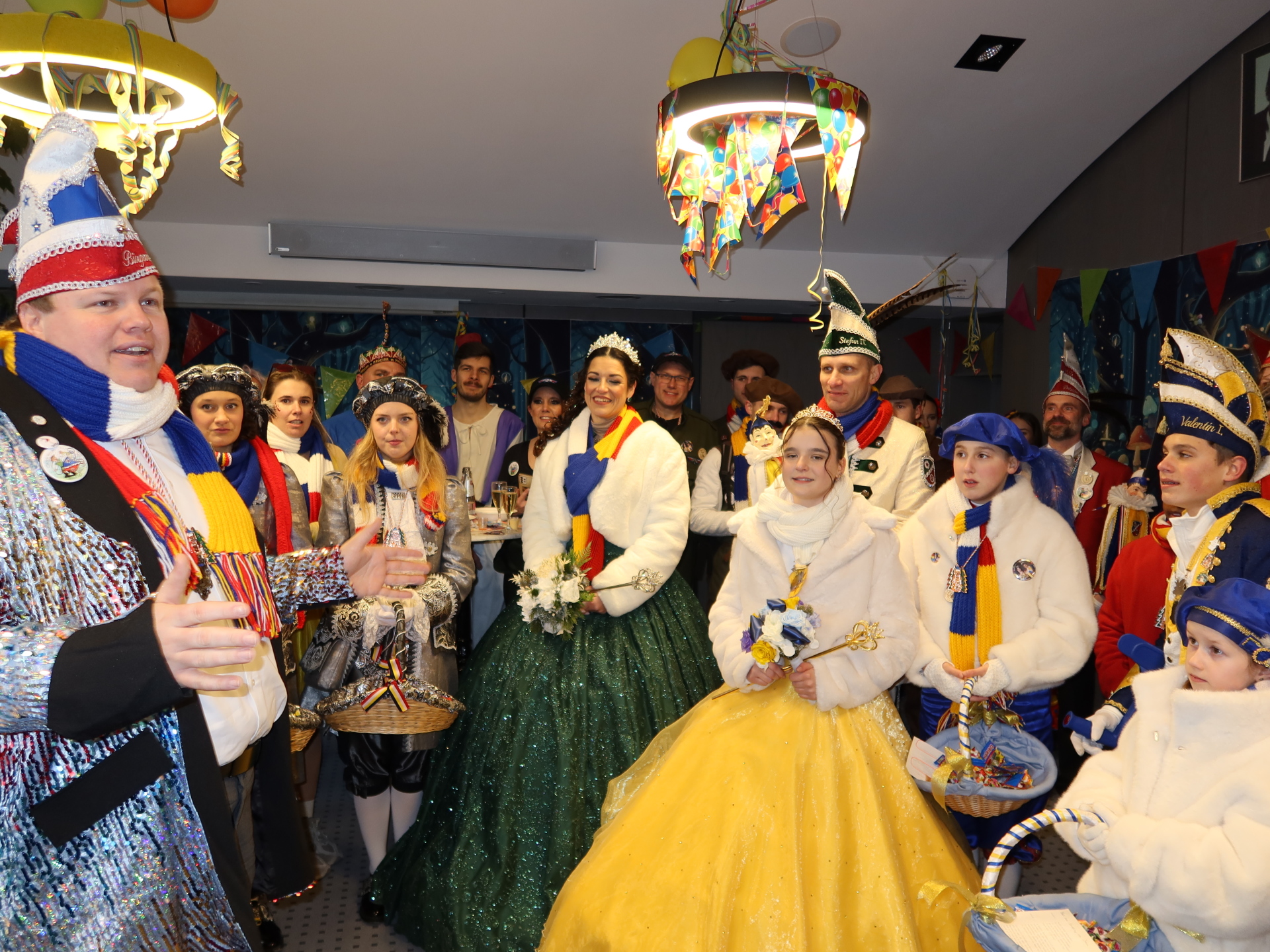 Prince and princess couple and children's prince and princess couple with mayor with colourful hats, sashes and dresses in the magistrate's meeting room after the jesters successfully took over the town hall