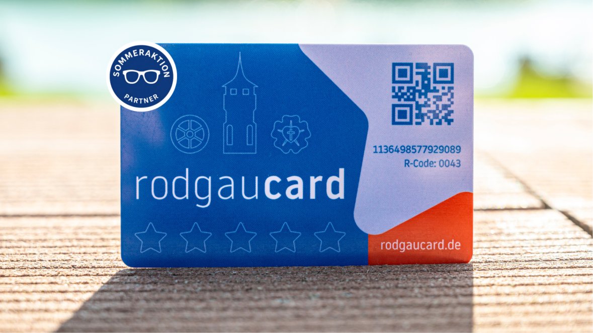 Tarjetas Rodgaucards azules con texto en blanco, un código QR, símbolos y la inscripción «Promoción de verano para socios» sobre un fondo de madera