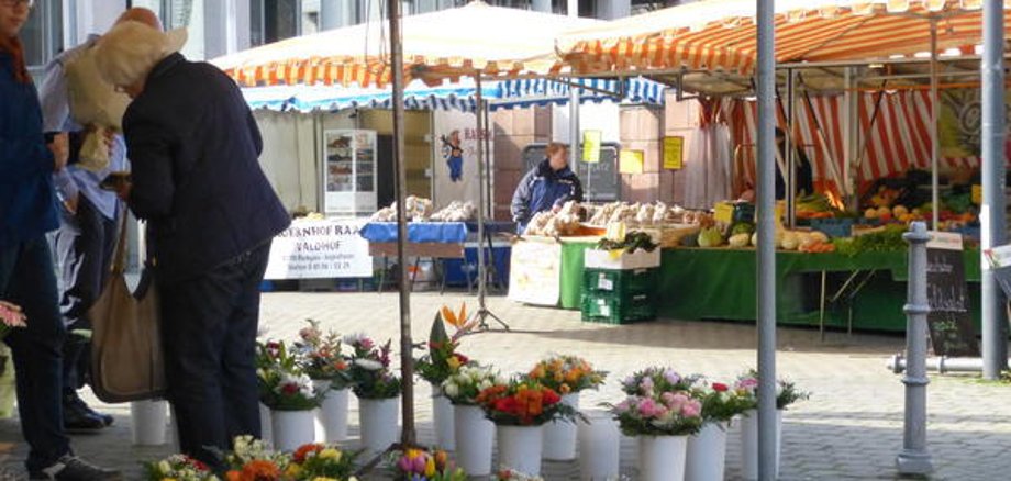 Mercado semanal en Jügesheim con puestos de flores, verduras y productos de panadería bajo toldos a rayas