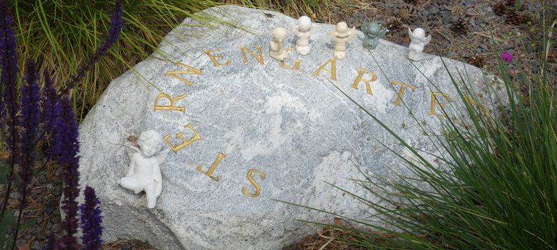 Una piedra con la inscripción Sternenkinder. En el borde superior se pueden ver pequeñas esculturas de ángeles.