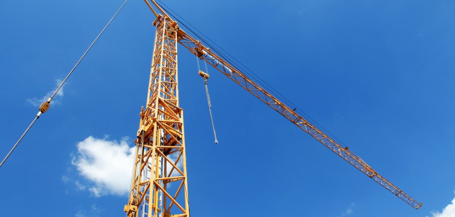 Haute grue de construction jaune sur fond de ciel bleu avec quelques nuages blancs