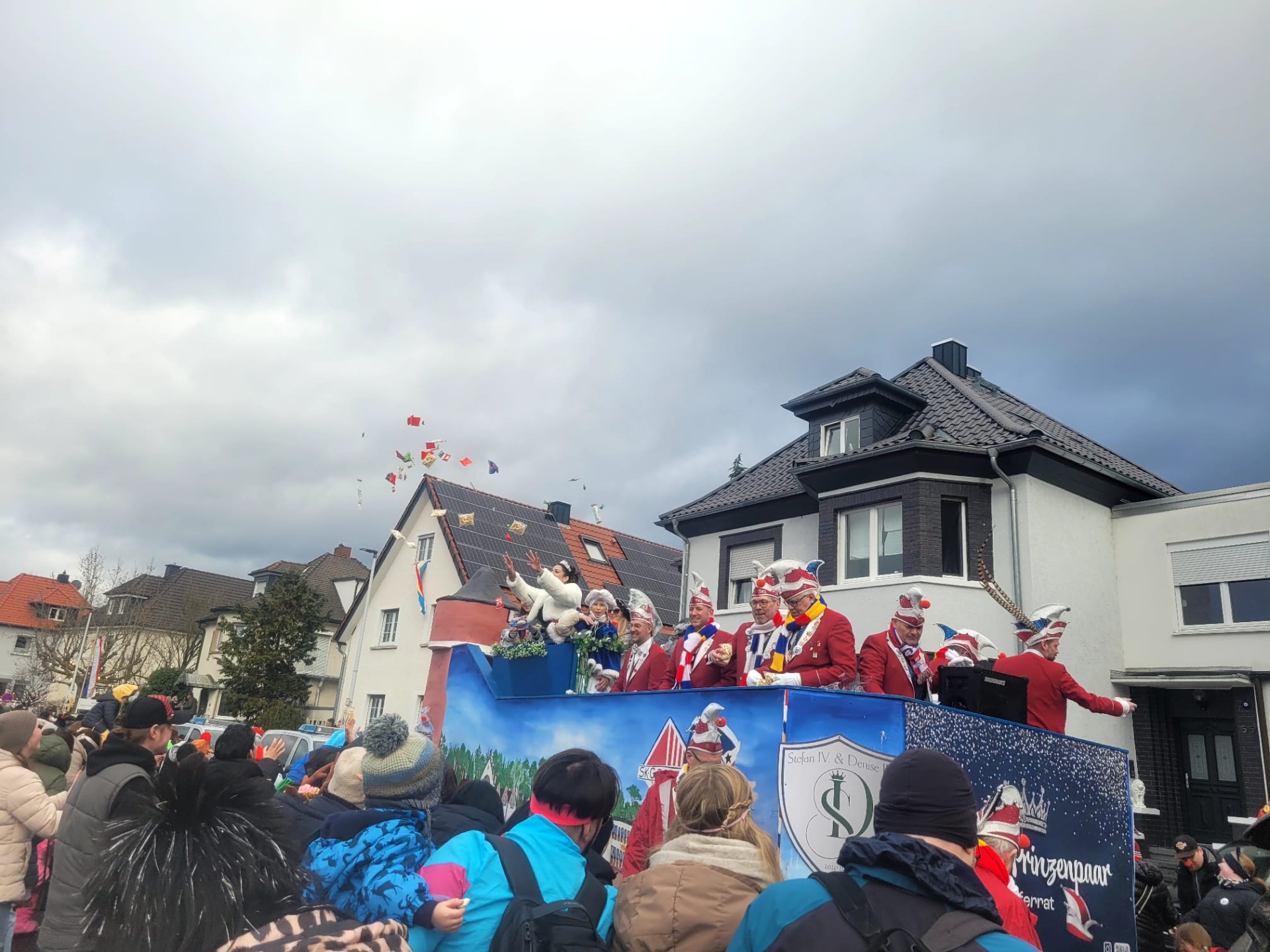 Le conseil des onze et la princesse sur un char de carnaval décoré pendant le défilé du carnaval 2026, entourés de spectateurs en vêtements d'hiver devant des habitations.