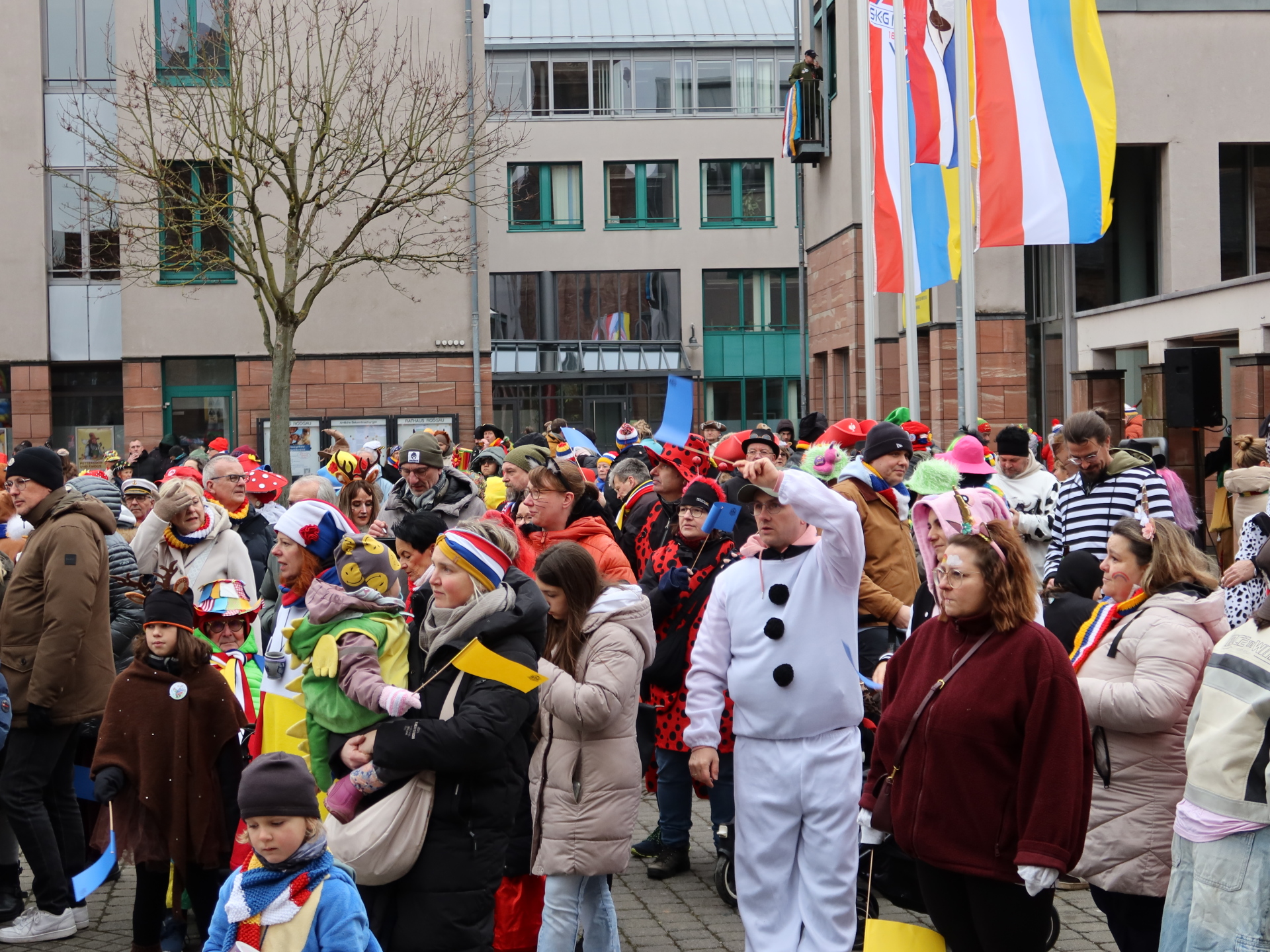 Foule en costumes colorés lors de la prise de l'hôtel de ville avec un mât et plusieurs drapeaux