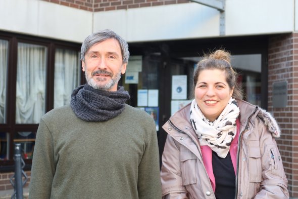 Un homme et une femme se tiennent devant un bâtiment
