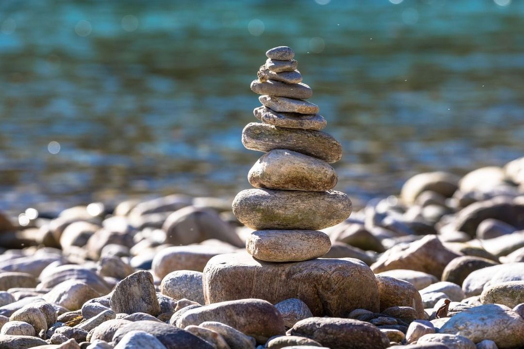 Torre di pietre accatastate su un letto di ghiaia su uno sfondo d'acqua sfuocato