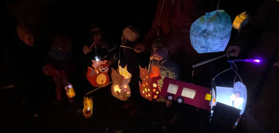 Lanterne colorate alla sfilata delle lanterne Al calar della notte, diversi bambini tengono in mano lanterne colorate a forma di animali e veicoli