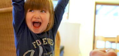 Un bambino che ride allunga le mani in aria Bambino che ride alza le mani in aria - sullo sfondo un asilo nido