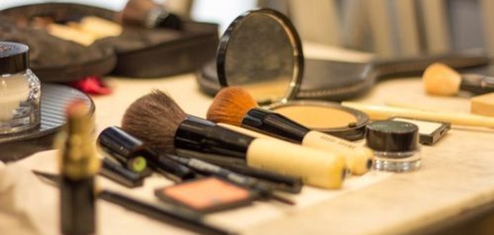 Akcesoria do makijażu Pędzle do makijażu, szminka, puder w kompakcie oraz inne produkty kosmetyczne ułożone na stole