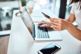 Osoba trzyma kartę kredytową nad klawiaturą laptopa i korzysta z usługi online