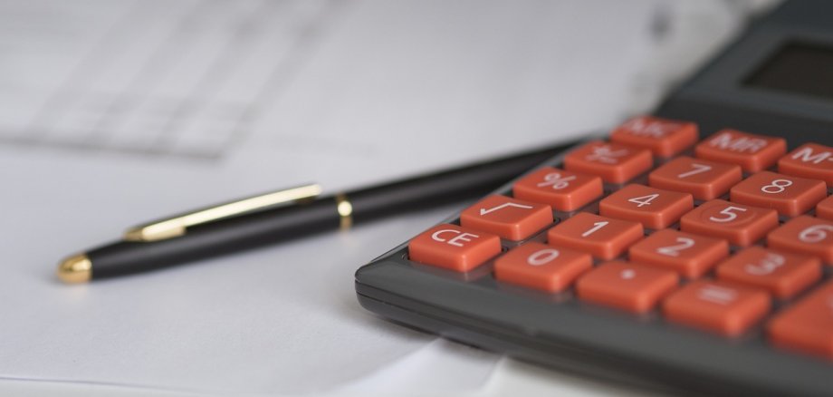 Gospodarstwo domowe Kalkulator z czerwonymi klawiszami i czarnymi długopisami na papierze, symbolizuje gospodarstwo domowe