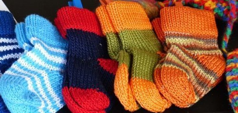 Meias de malha Várias meias tricotadas à mão, em várias cores e padrões, alinhadas lado a lado