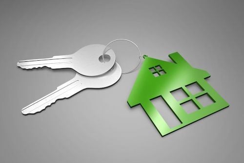 Două chei argintii cu un breloc de care atârnă simbolul unei case verzi cu ferestre.