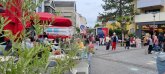 Puiseauxplatz İnsanlar Puiseauxplatz'daki dondurma salonunun önünde oturuyor. Ön planda bitkiler ve yan tarafta yoldan geçenler var.