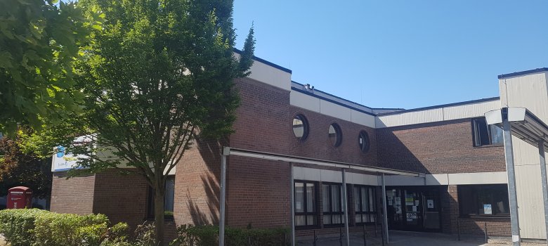 Niederroden Sosyal Merkezi Niederroden sosyal merkezinin tuğla cepheli giriş alanı, birkaç yuvarlak pencere ve ön planda ağaçlar