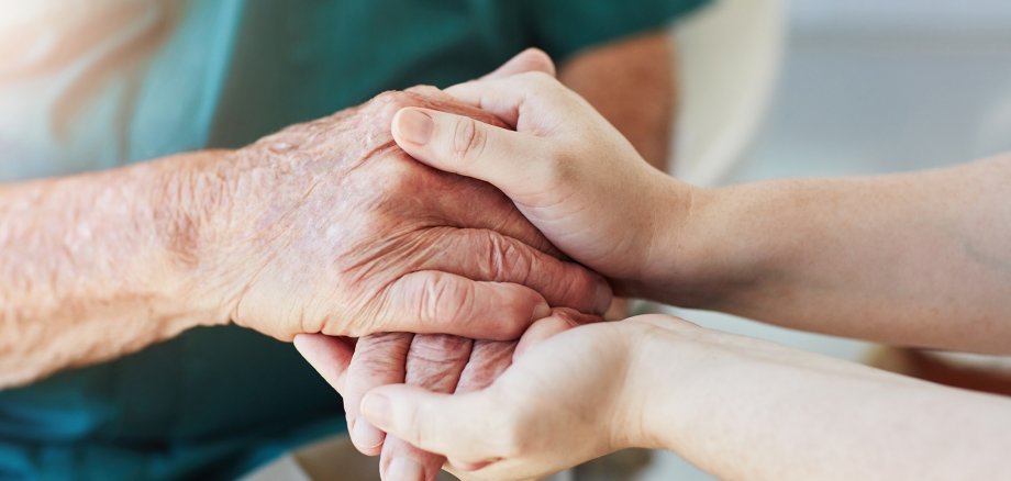 Молодші руки тримають руки старшої людини.