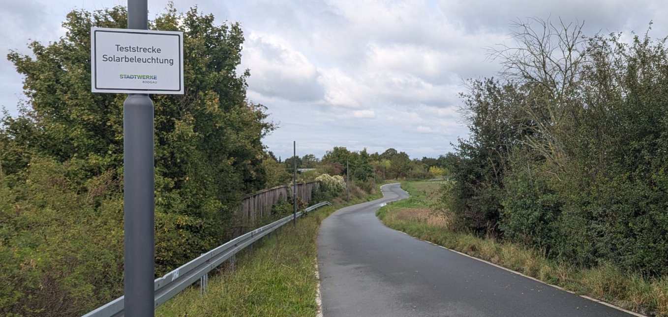 Teststrecke Solarbeleuchtung Weiskirchen Feldweg von der Mollischgrabenbrücke zur Schillerstraße. Links im Vordergrund ist ein Mast mit dem Hinweisschild "Teststrecke Solarbeleuchtung".