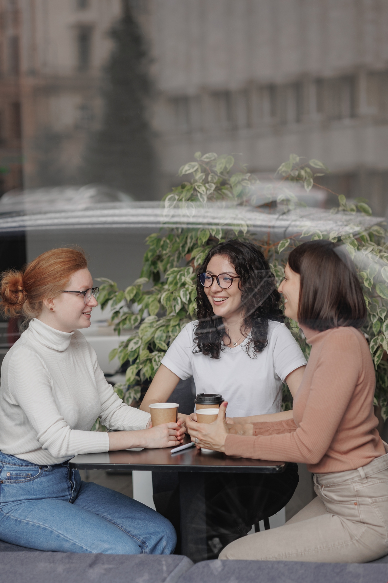 three female friends are talking in a coffee shop and drinking tea, moral support and caring friendship. mental health