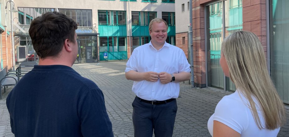 Bürgermeister Max Breitenbach spricht mit zwei Personen auf dem Innenhof des Rathauses