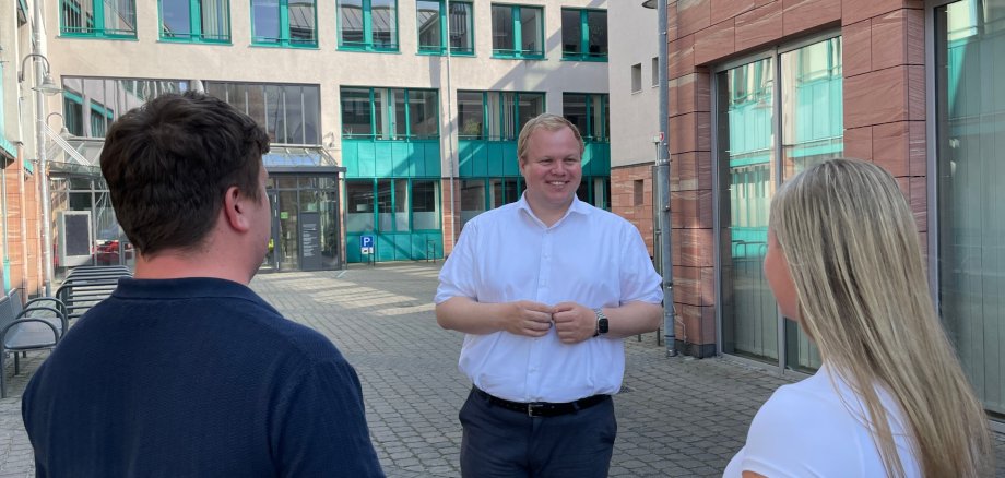 Bürgermeister Max Breitenbach spricht mit zwei Personen auf dem Innenhof des Rathauses