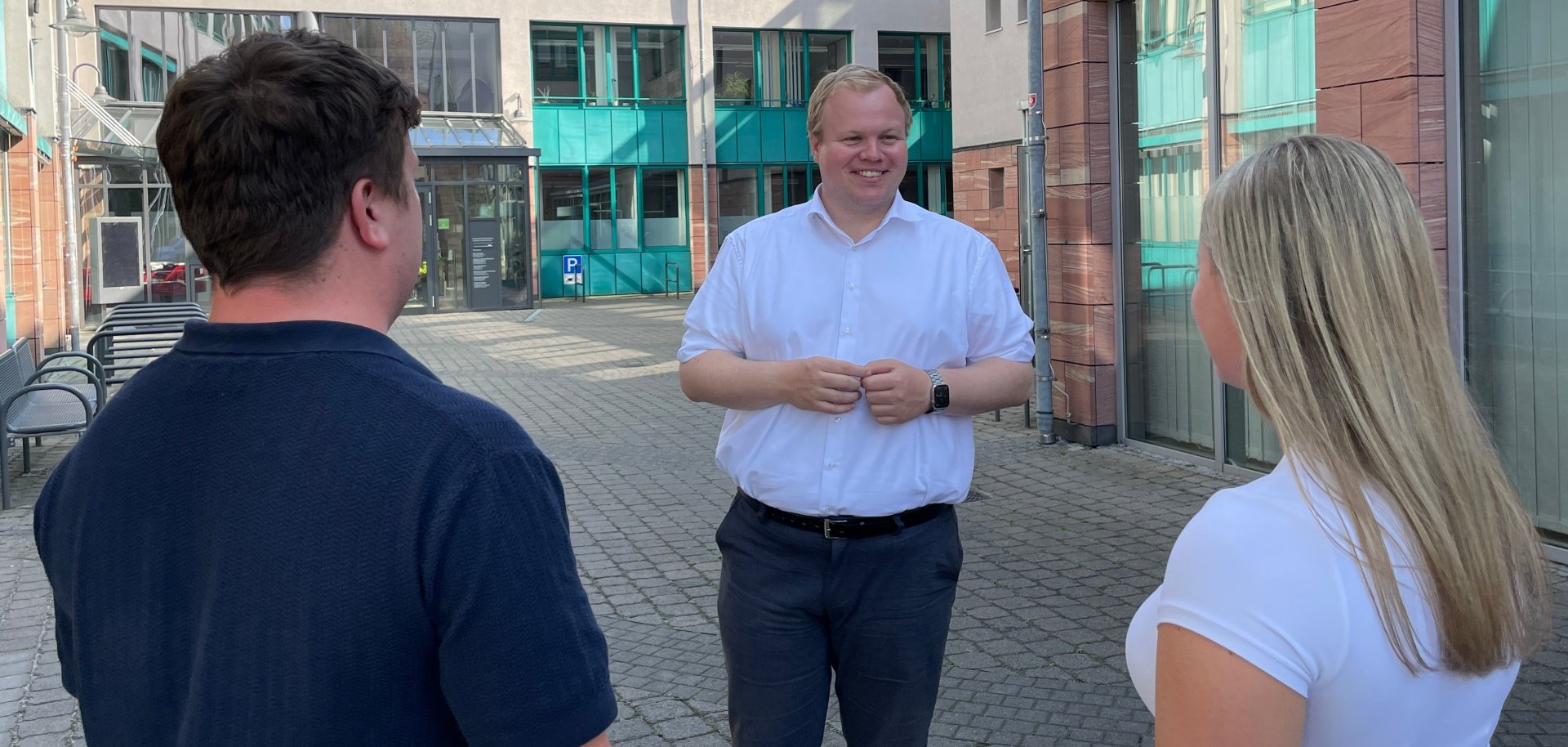 Bürgermeister Max Breitenbach spricht mit zwei Personen auf dem Innenhof des Rathauses