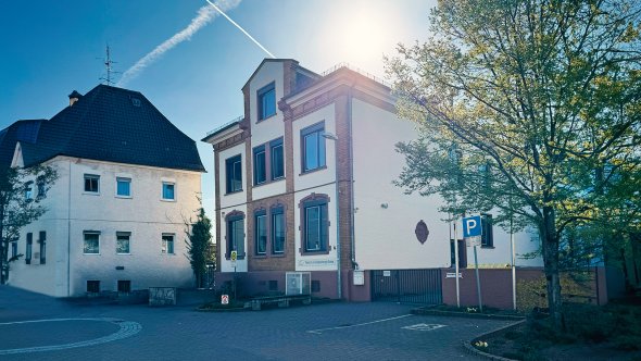 Ein Altes Haus,  worin die Bodelschwing-Schule untergebracht ist. Davor ist ein großer gepflasterter Vorplatz, ein großer Baum und die Sonne scheint