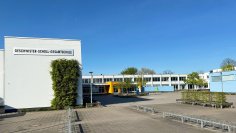 Die Schule im Hintergrund, davor ein großer Schulhof und viele Fahrradständer