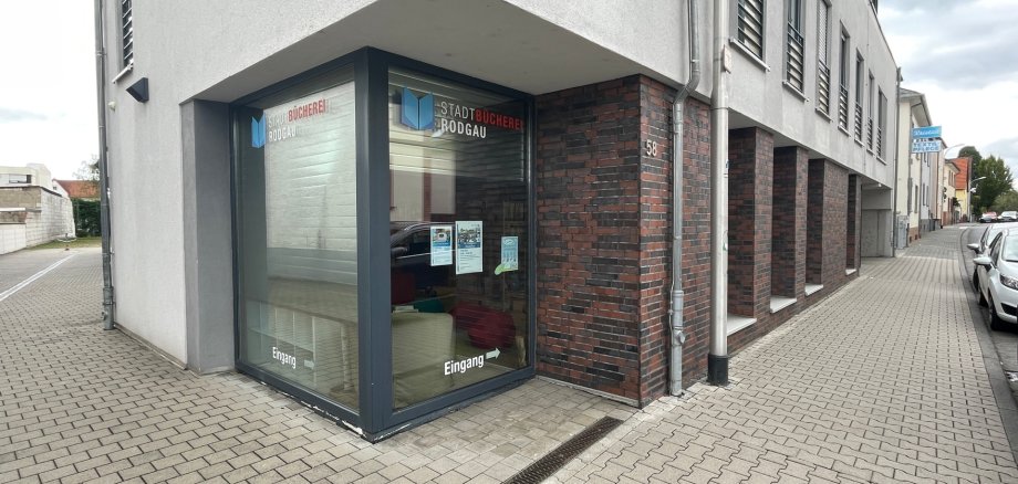 Eingang der Stadtbücherei Jügesheim in einem modernen Gebäude mit Glasfront und Hinweisschildern