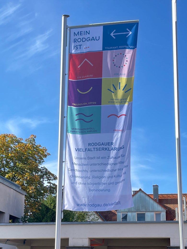 Vielfaltsfahne mit Aussagen zur Vielfalt in Rodgau, darunter 'Mein Rodgau ist ...', verschiedene Symbole und die Rodgauer Vielfaltserklärung am Bürgermeister-Hermann-Sahrm-Platz