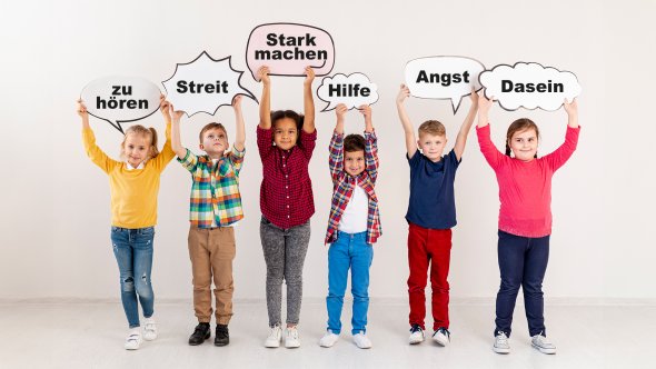 Sechs Kinder stehen nebeneinander und halten Schilder mit den Worten 'zu hören', 'Streit', 'Stark machen', 'Hilfe', 'Angst' und 'Dasein' hoch