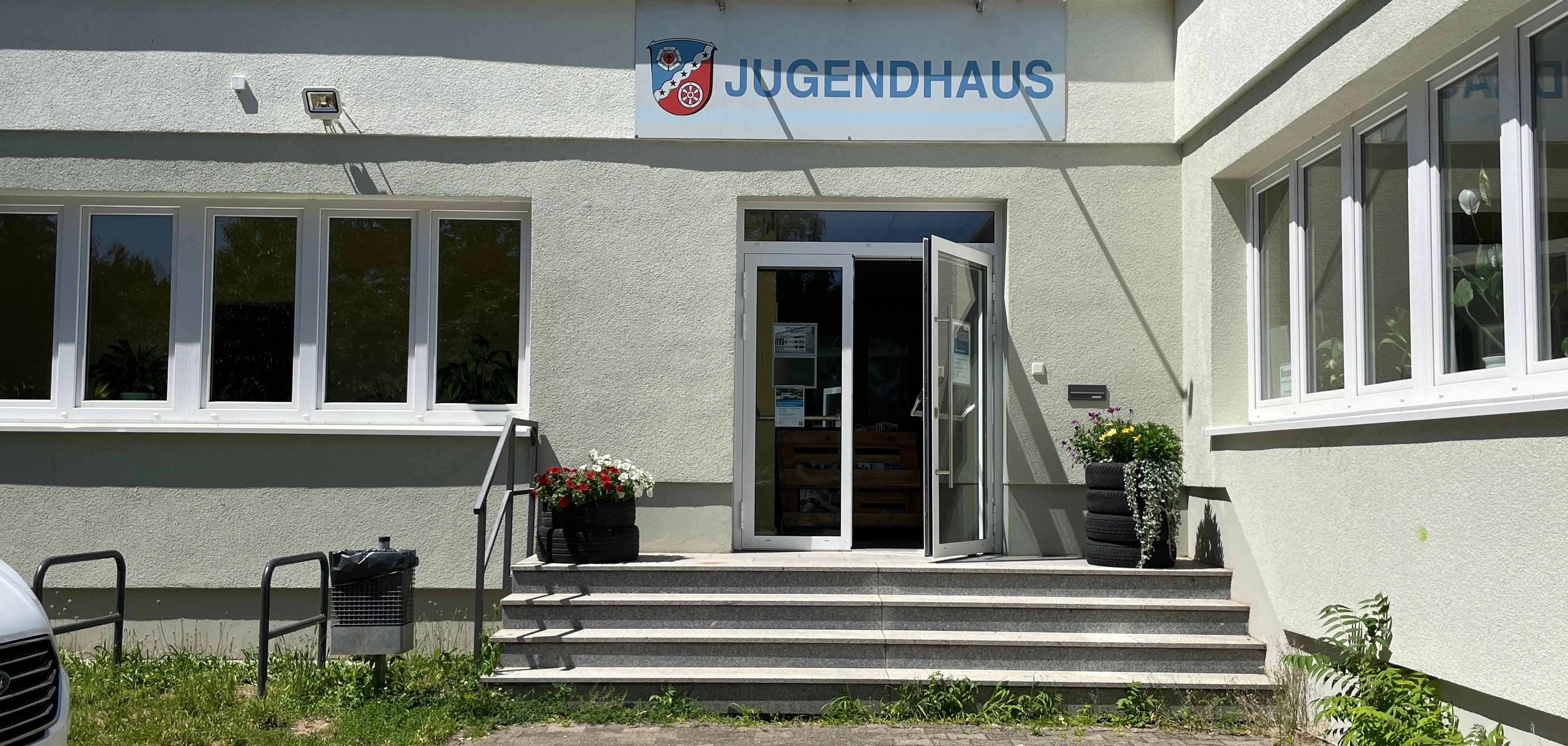 Das Gebäude des Jugendhauses in Dudenhofen  im Bereich des Eingangs mit Treppenstufen und Fahrradständern zur Linken.