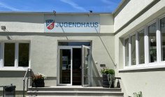 Das Gebäude des Jugendhauses in Dudenhofen  im Bereich des Eingangs mit Treppenstufen und Fahrradständern zur Linken.