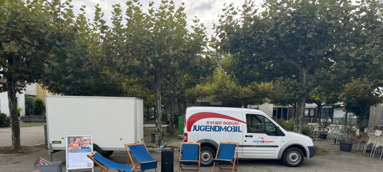 Das Jugendmobil mit Anhänger steht mit Sonnenstühlen auf dem Puiseauxplatz