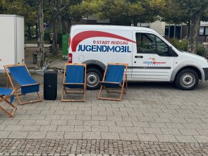 Das Jugendmobil mit Anhänger steht mit Sonnenstühlen auf dem Puiseauxplatz