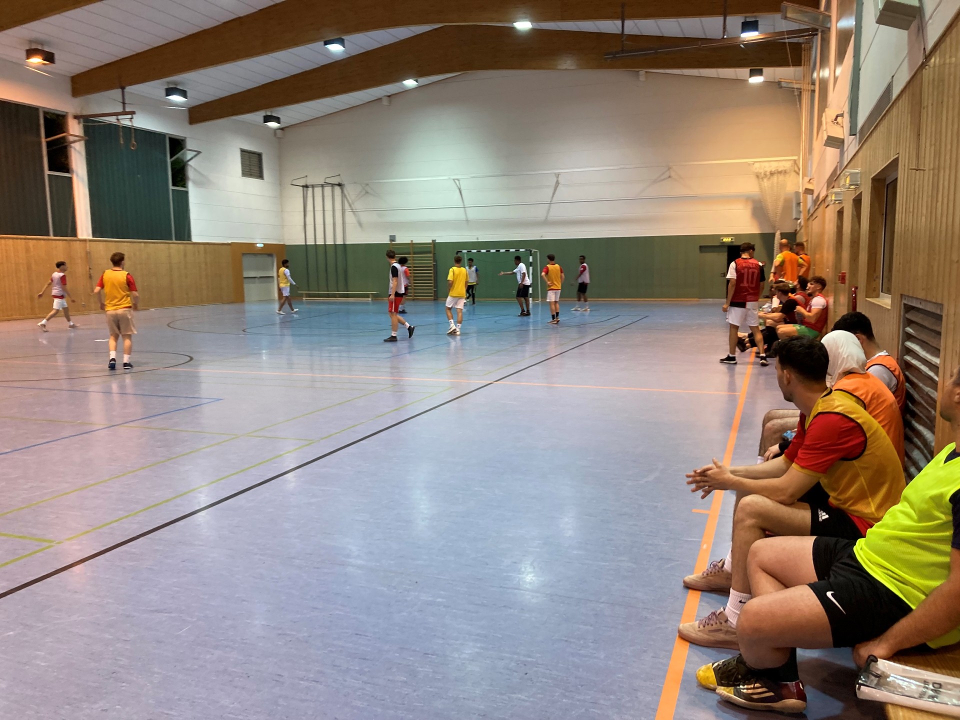 Jugendliche spielen Hallenfußball Jugendliche spielen Hallenfußball in einer Sporthalle, einige sitzen auf der Bank und schauen zu