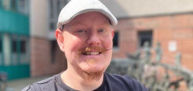Herr Pieper vom Team der Jugendarbeit im Rathausinnenhof. Er trägt eine weiße Basecap sowie einen Schnurrbart