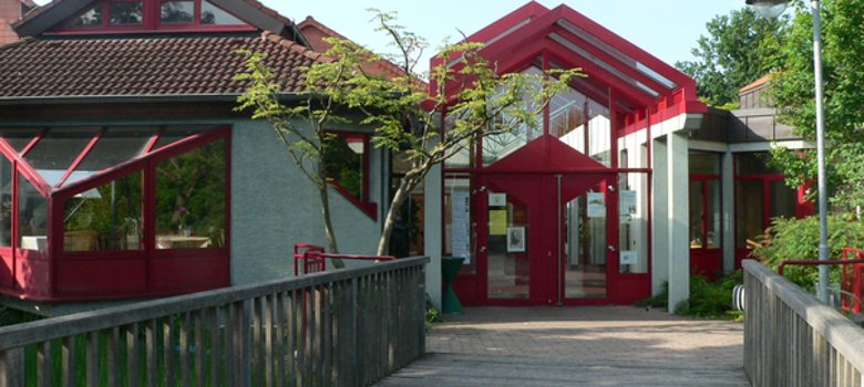 Bürgerhaus Weiskirchen Eingangsbereich des Bürgerhauses Weiskirchen mit rotem Glasvordach und Holzbrücke im Vordergrund