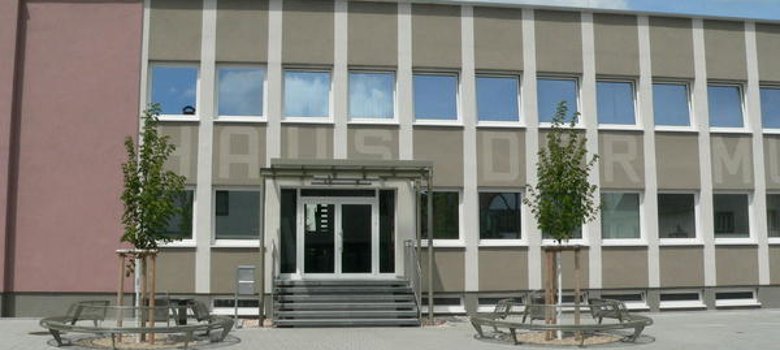 Haus der Musik Fassade des Hauses der Musik mit Eingangsbereich, zwei Bäumen und Sitzgelegenheiten davor