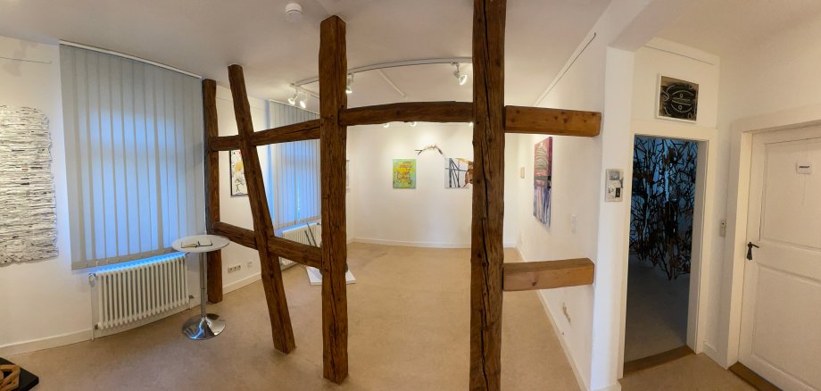 Innenraum der Rodgau Galerie mit weißen Wänden, mehreren Kunstwerken an den Wänden und einer hölzernen Fachwerkstruktur in der Mitte