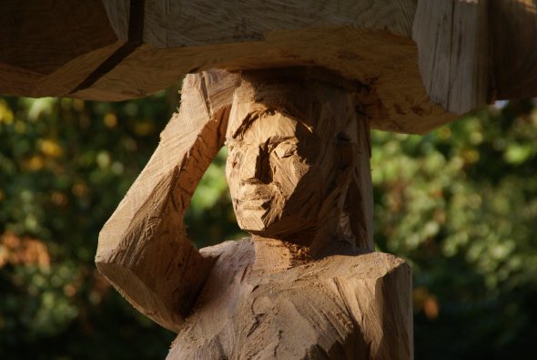 Holzskulptur einer nachdenklichen Person mit erhobener Hand im Rodaupark