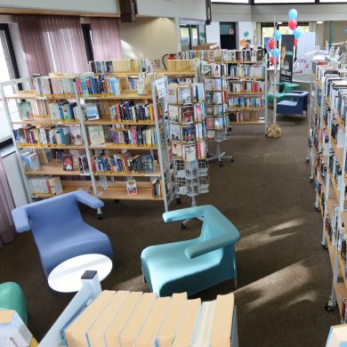 Weitläufiger Raum mit Bücherregalen und Sitzgelegenheiten in der Stadtbücherei Nieder-Roden.