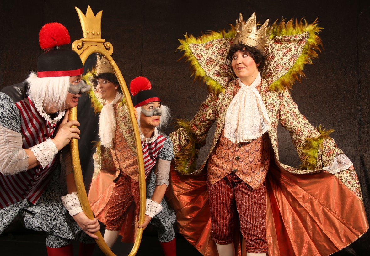 Drei kostümierte Personen mit Clownschminke, die in einer Theaterszene dargestellt werden