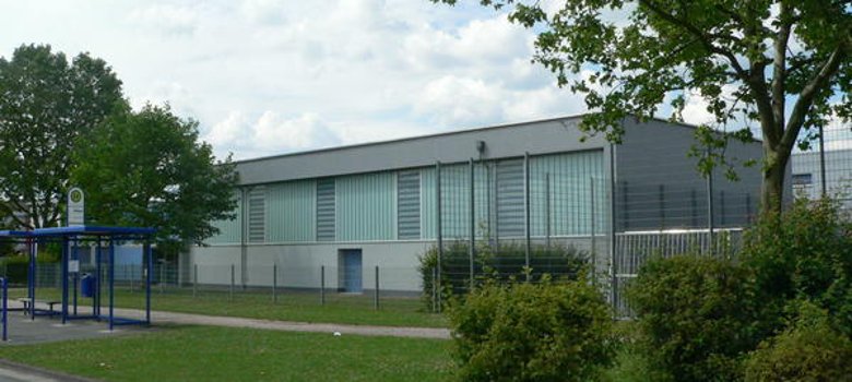 Turnhalle Sicht auf die Turnhalle Münchshausen-Schule, ein großes Gebäude mit einem umgebenden Zaun.