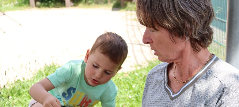 Projekt Wunsch-Großeltern Eine Teilnehmerin des Projektes Wunsch-Großeltern spielt im Freien auf einer grünen Wiese mit Ihrem "Wunsch-Enkel".