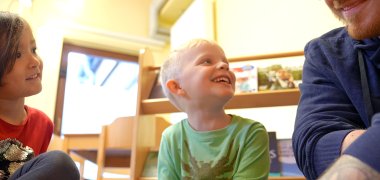 Sozialassistent lacht mit zwei Kindern