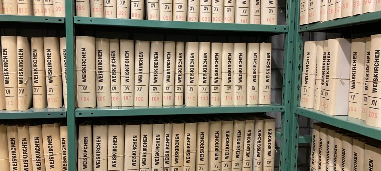 Archivbestände Archivbestände mit nummerierten Ordnern beschriftet 'WESKIRCHEN' in Regalen