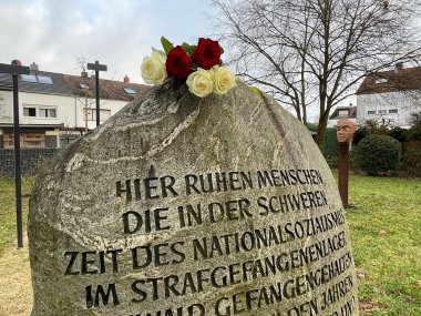 Gedenkstein Gedenkstein mit der Inschrift zu Opfern des Nationalsozialismus in einem Strafgefangenenlager, mit roten und weißen Rosen darauf