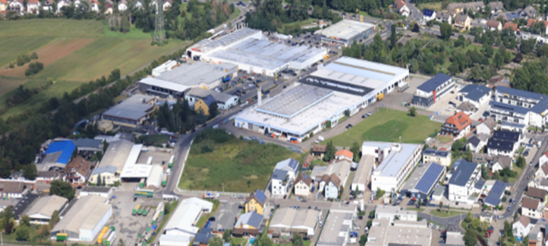 Luftaufnahme des Gewerbegebiets Dudenhofen mit Hegelstraße, Raiffeisenstraße und Kronberger Straße, umgeben von Wohngebieten und Feldern.